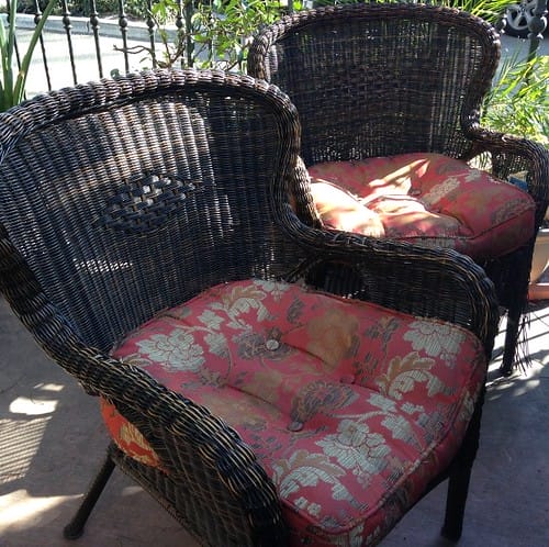 2 rattan chairs with red pillows